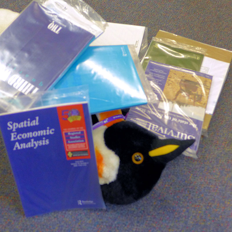 Pablo Penguin partially buried by an avalanche of journals