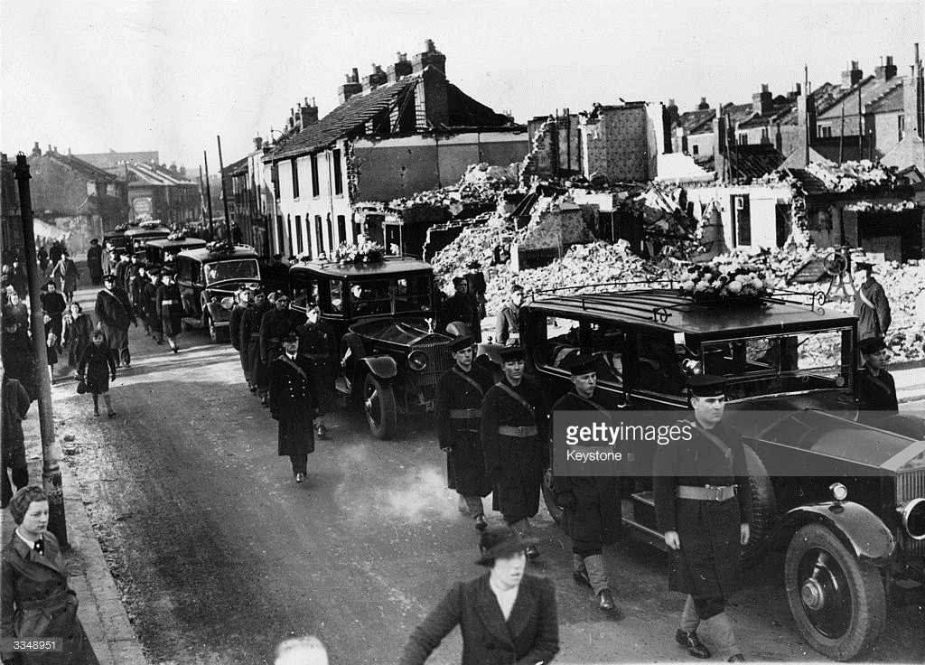 Getty images: Funeral cars drive slowly through a bomb-damaged street in Portsmouth, accompanied by an escort of British soldiers and sailors. Twenty-five victims of an air raid are to be buried in a common grave. bombing funeral 1941