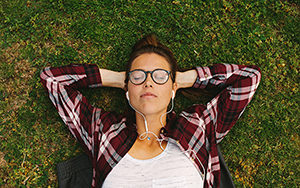 Woman relaxing on lawn listening to earphones