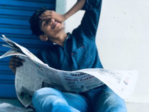 Young Indian man reading a newspaper